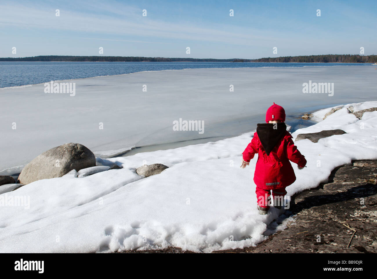 Kind am Ufer des Sees im Frühjahr, Paijanne, Finnland Stockfoto