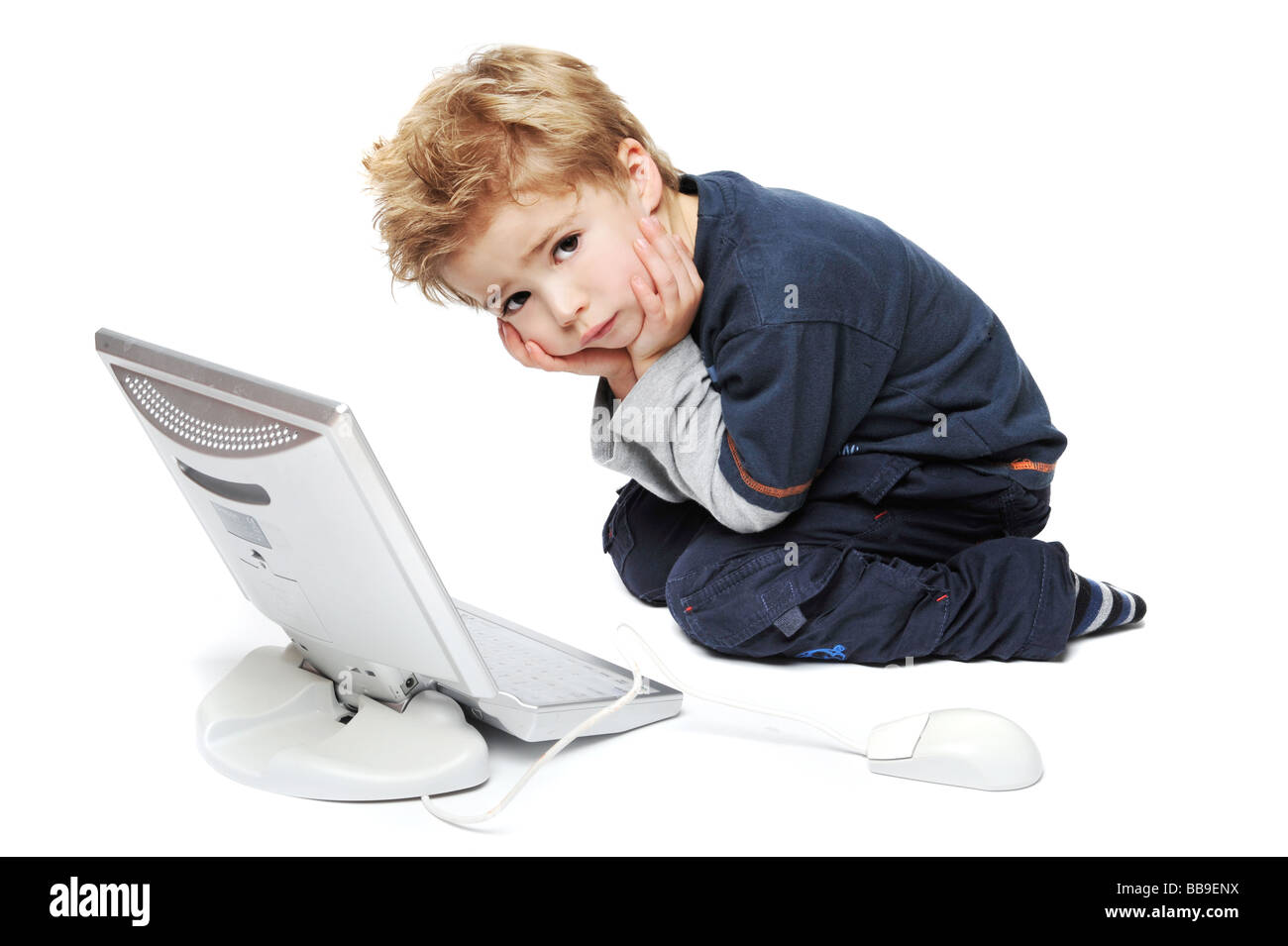 Kleiner junge Kind betrachten Arbeit auf seinem Computer in einem Studio auf weißem Hintergrund Stockfoto