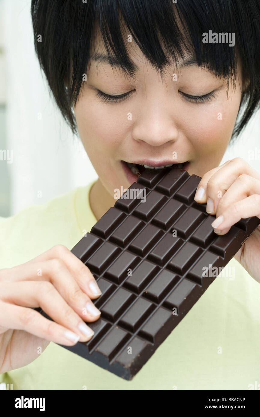 Eine Frau in einer Tafel Schokolade beißen Stockfoto