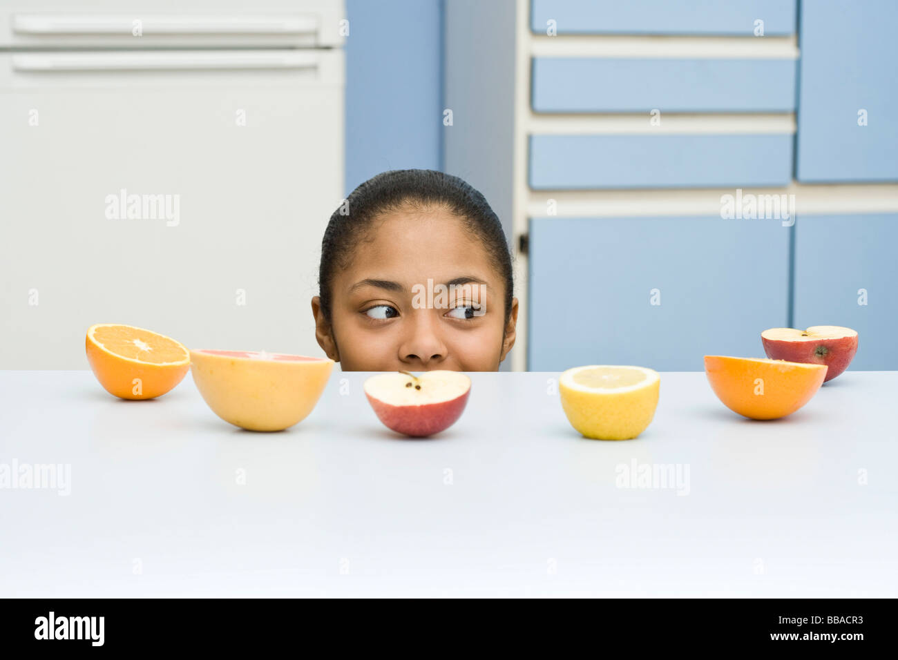 Eine junge Frau über einen Zähler mit Obst drauf spähen Stockfoto