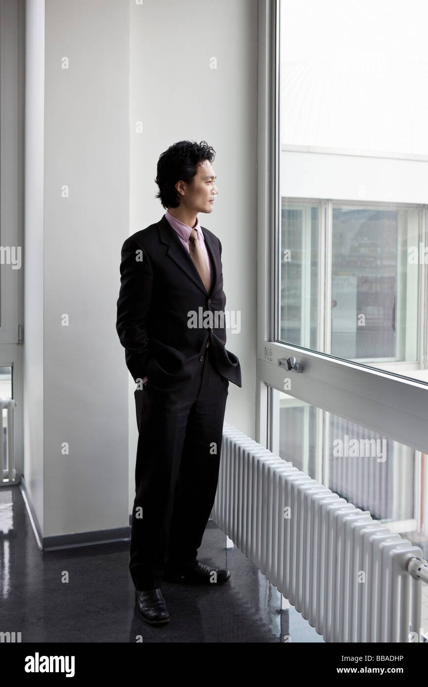 Ein Geschäftsmann, der Blick durch ein Fenster Stockfoto