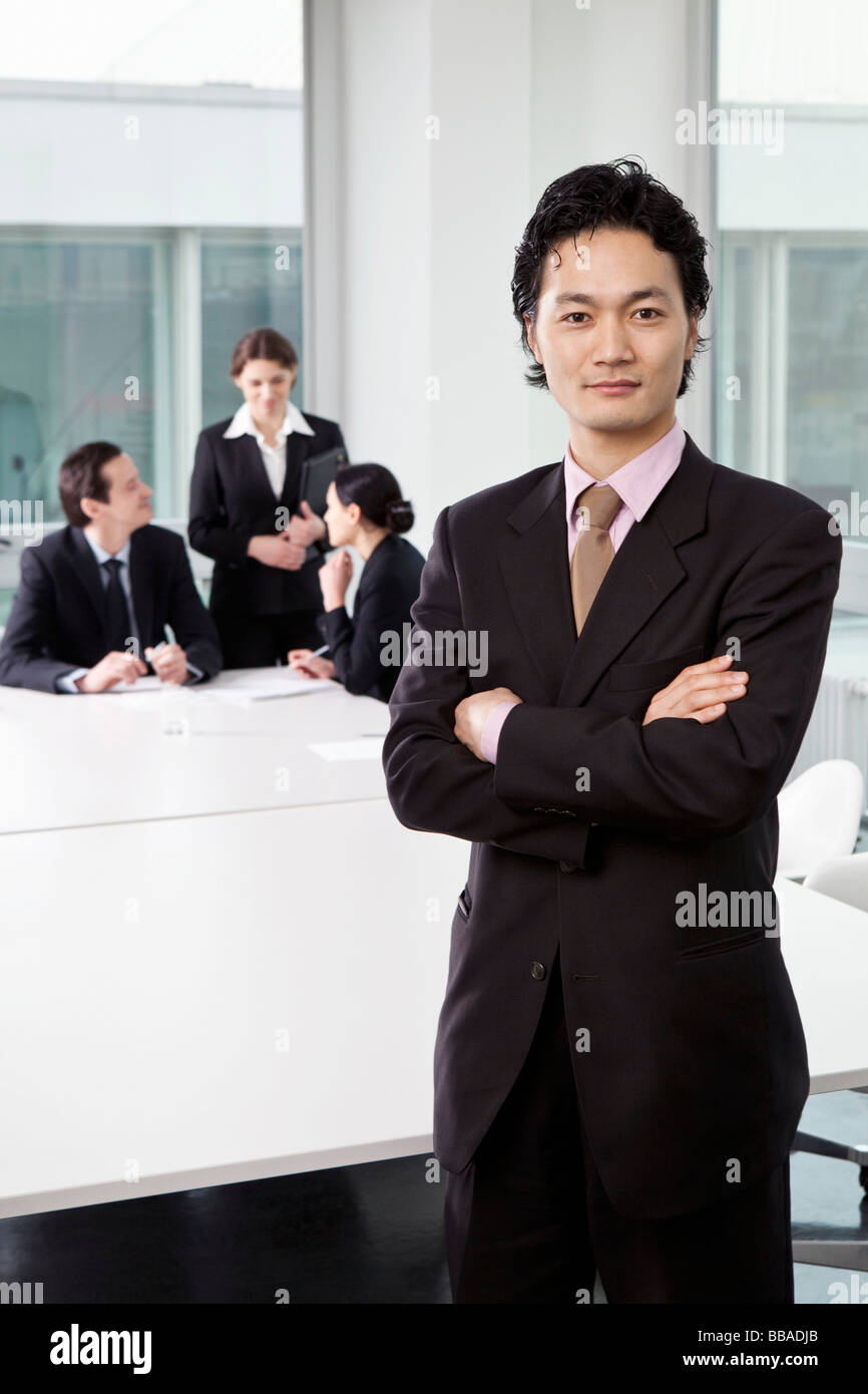 Porträt eines Geschäftsmannes in einen Sitzungssaal mit aus Fokus Business-Leute im Hintergrund Stockfoto