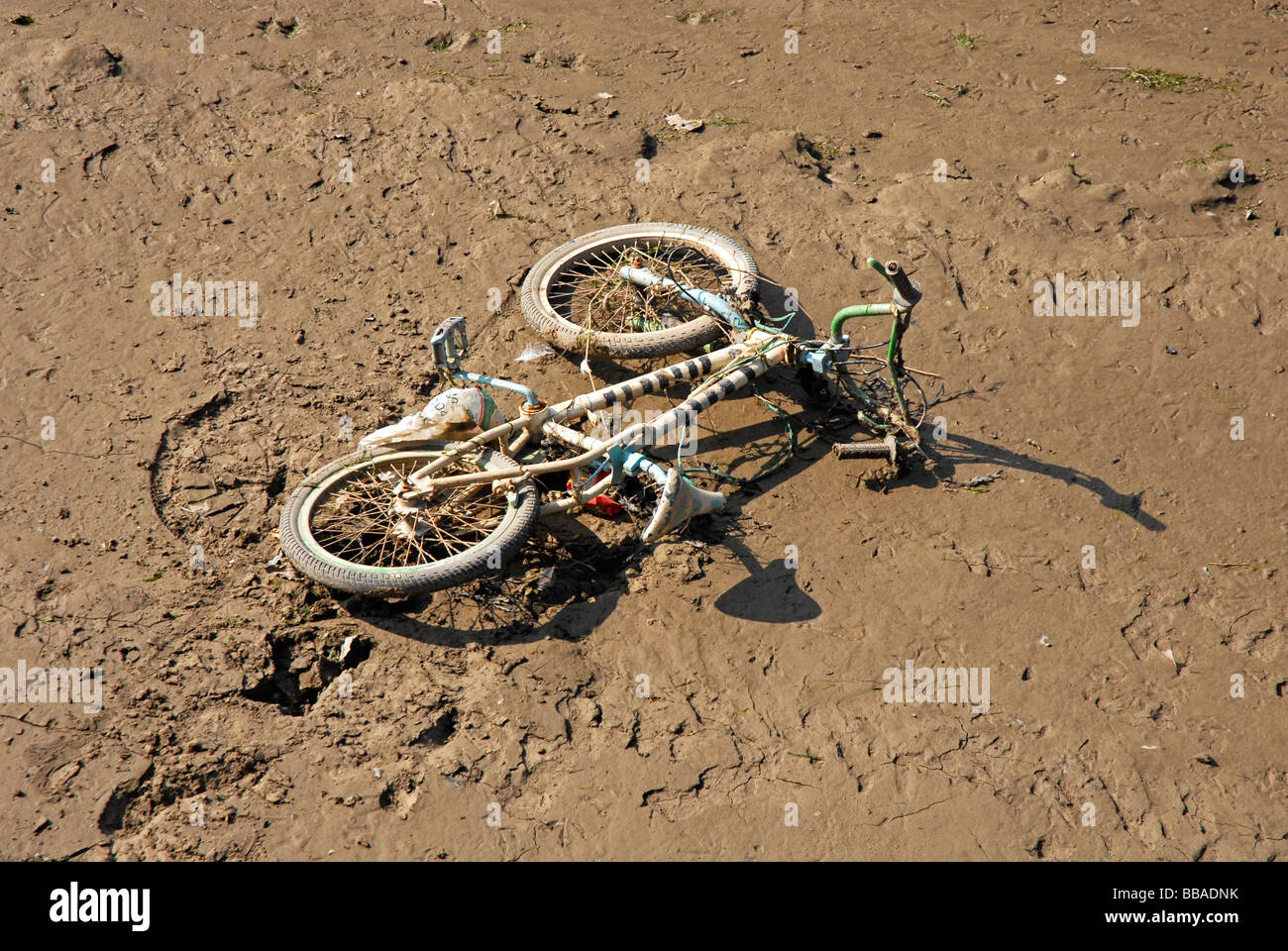 Gebrauchte Fahrrad in Schlamm auf Seite des Flusses Stockfoto