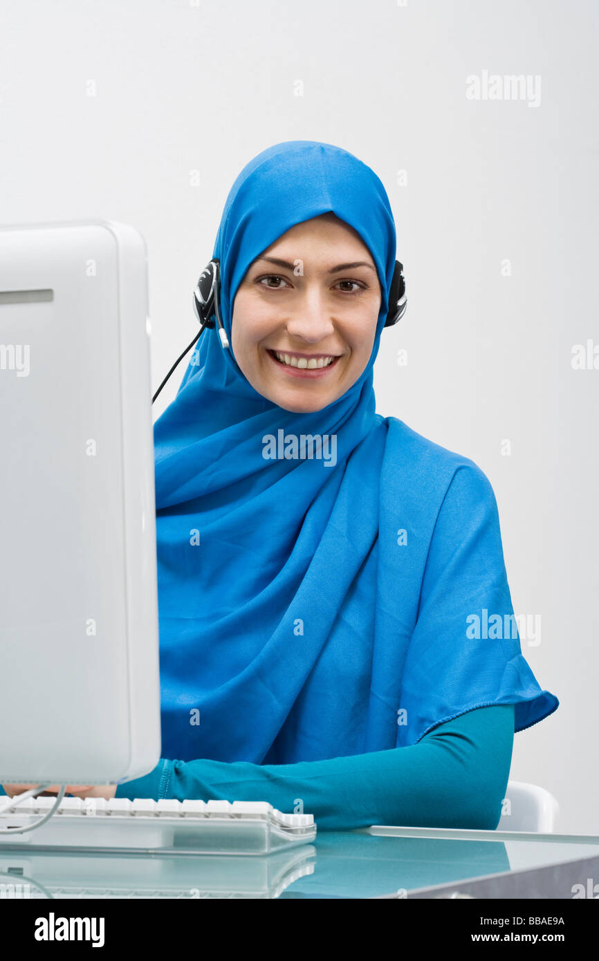 Eine Frau trägt ein Kopftuch und arbeitet in einem Callcenter Stockfoto