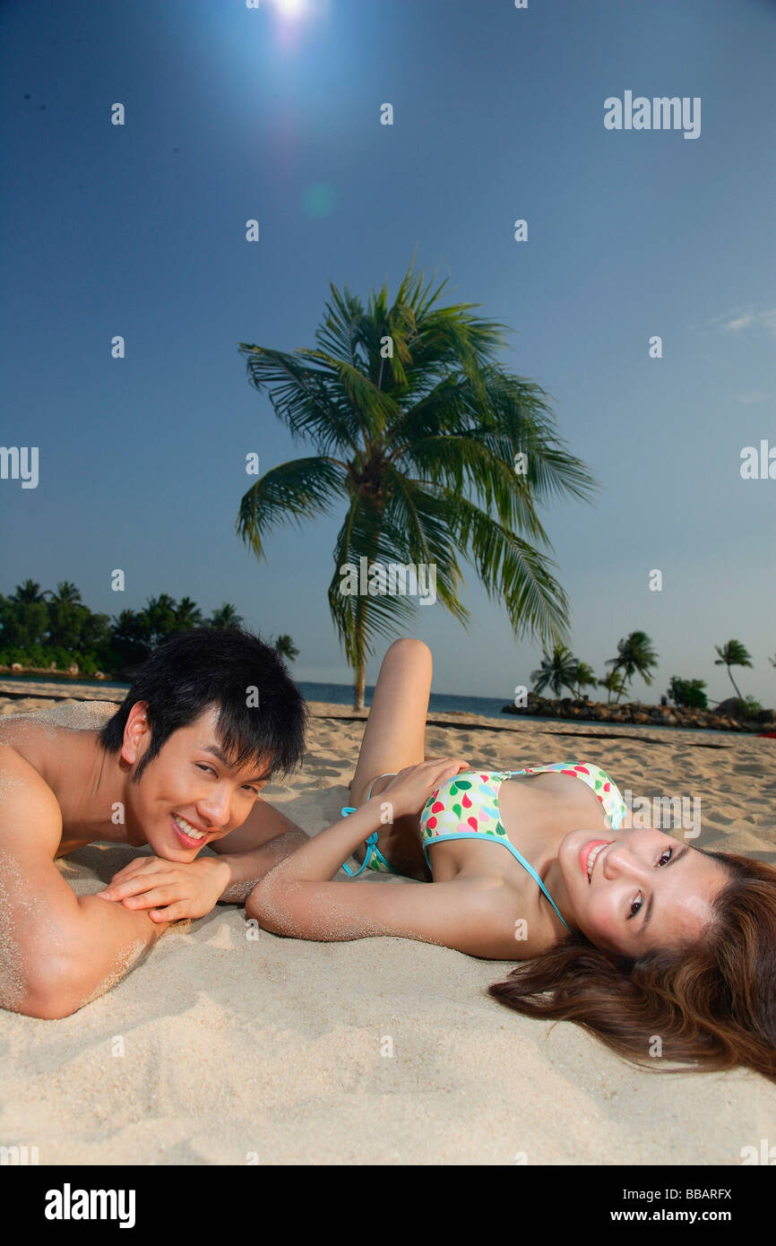 Junges Paar Verlegung auf Sand am Strand, Blick in die Kamera Stockfoto