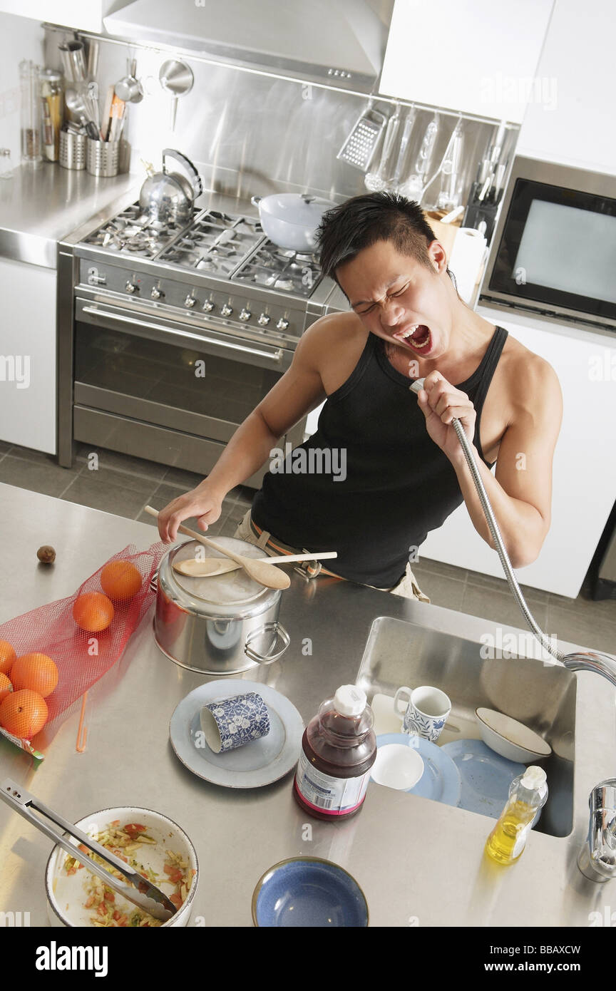 Junger Mann in der Küche, hält Hahn Schlauch, singen Stockfotografie - Alamy