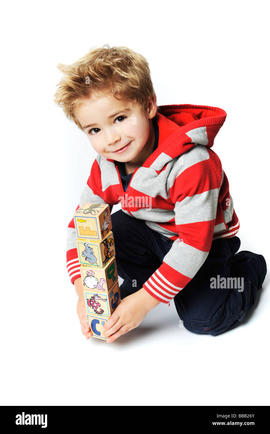 kleiner Junge mit seinen Bausteinen in rot auf weißem Hintergrund in die Kamera Lächeln Stockfoto