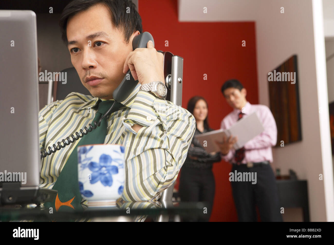 Geschäftsmann, sitzen vorne am Computer-Monitor, Menschen im Hintergrund Stockfoto