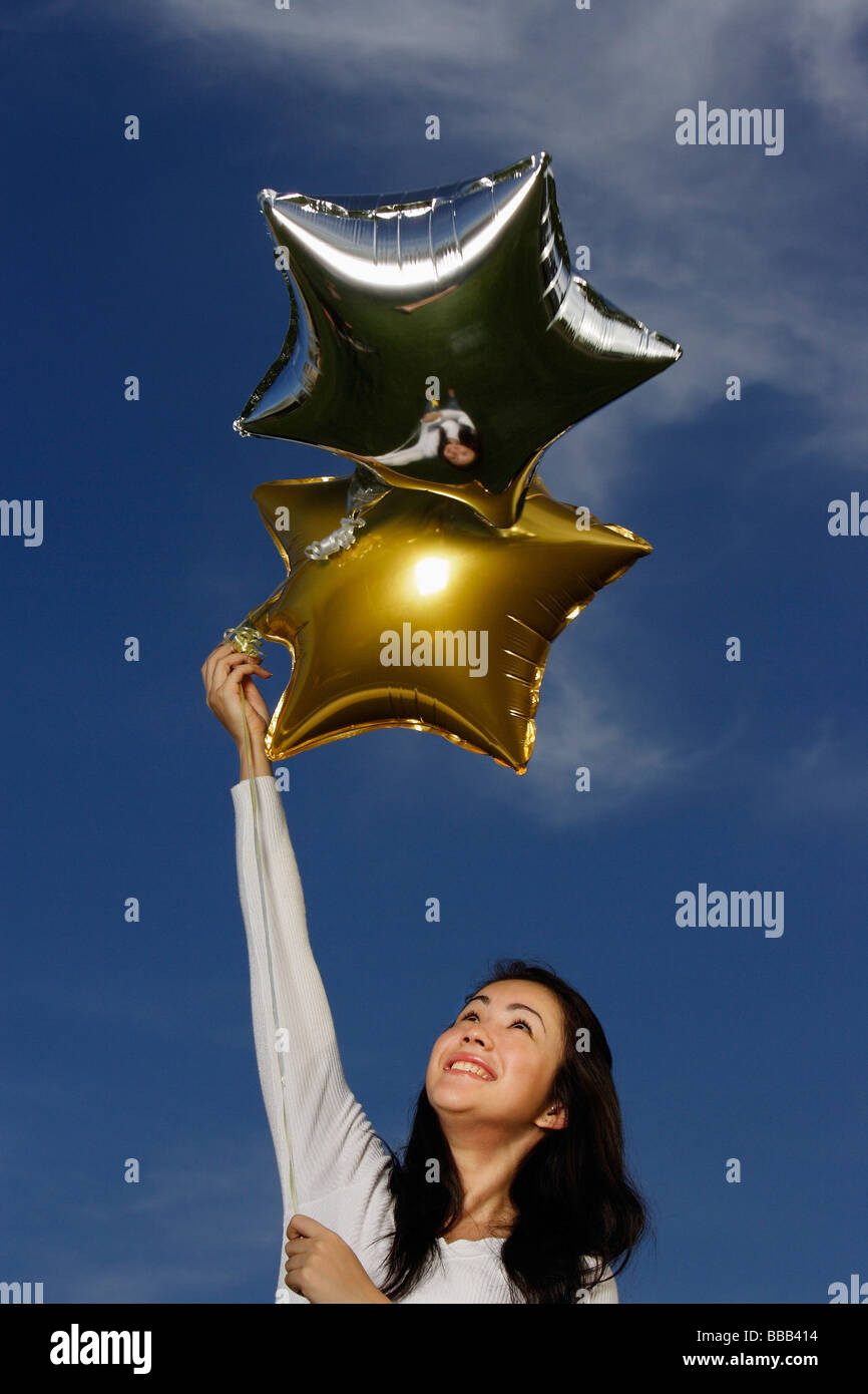 Junge Frau mit sternförmigen Luftballons Stockfoto