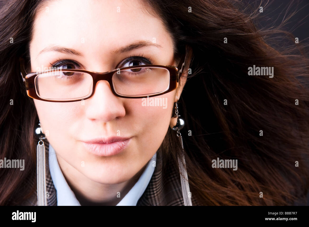 Junge Brünette Frau mit flatternden Haar Porträt auf dunklem Hintergrund Stockfoto