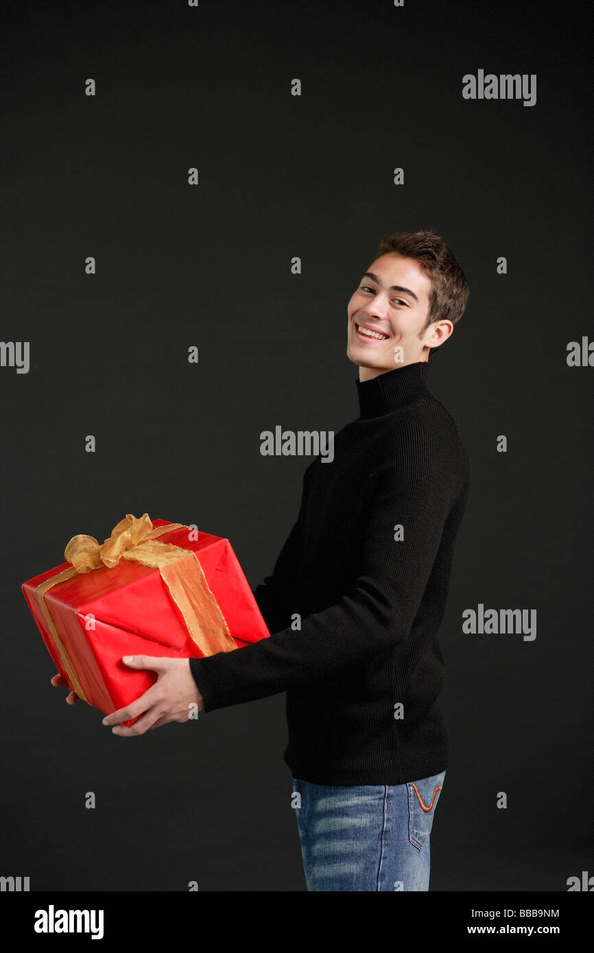 Mann im schwarzen Rollkragenpullover tragen rote Kiste mit Goldband Stockfoto