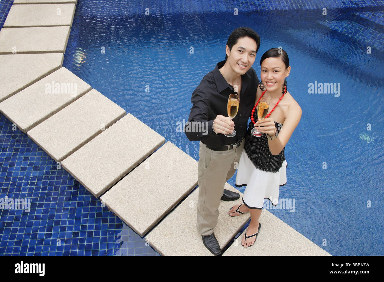 Paar stehen Swimmingpool, Kamera blickte, hält Champagner Gläser Stockfoto