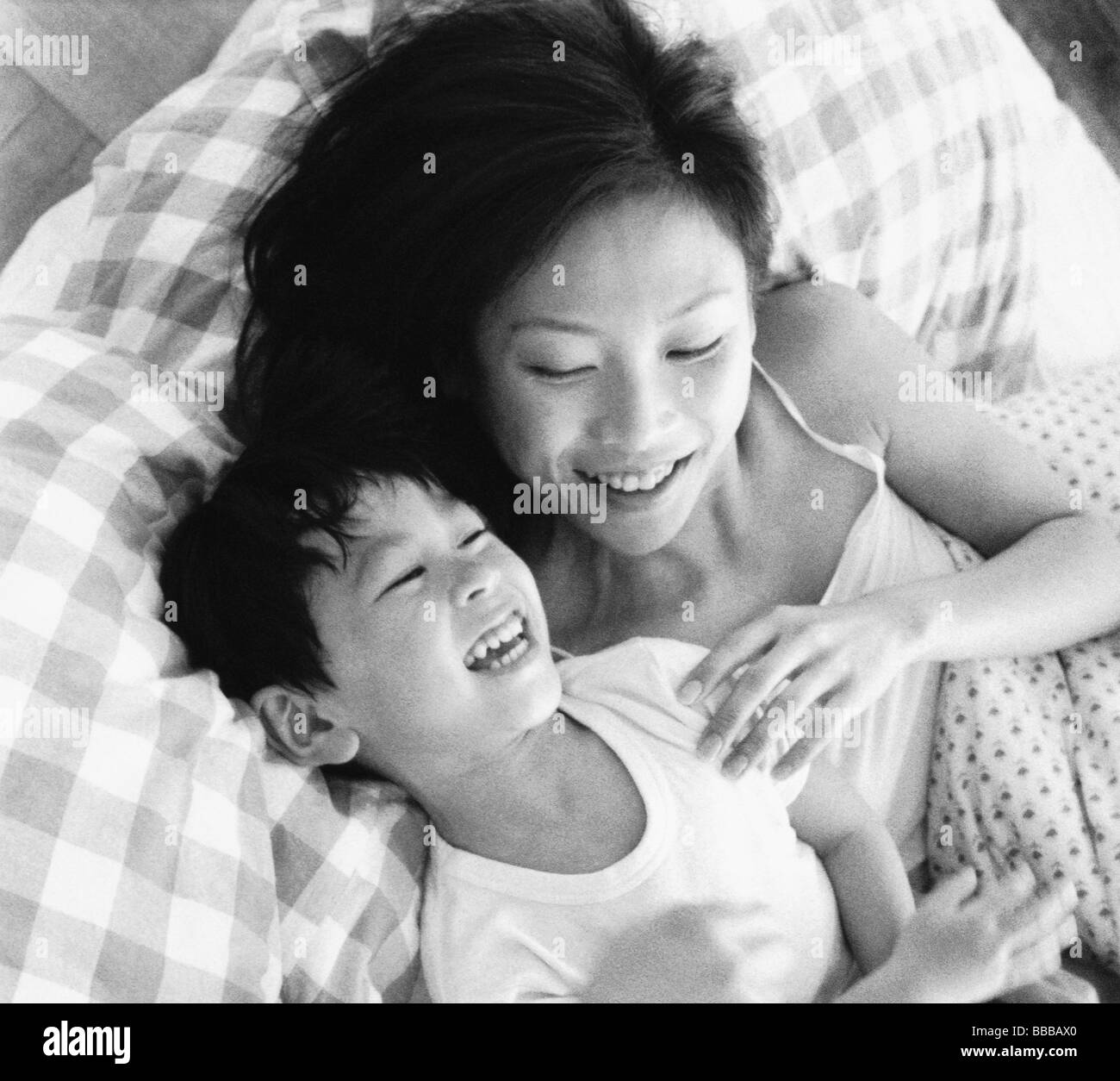 Mutter und Sohn im Bett spielen, lachen Stockfoto