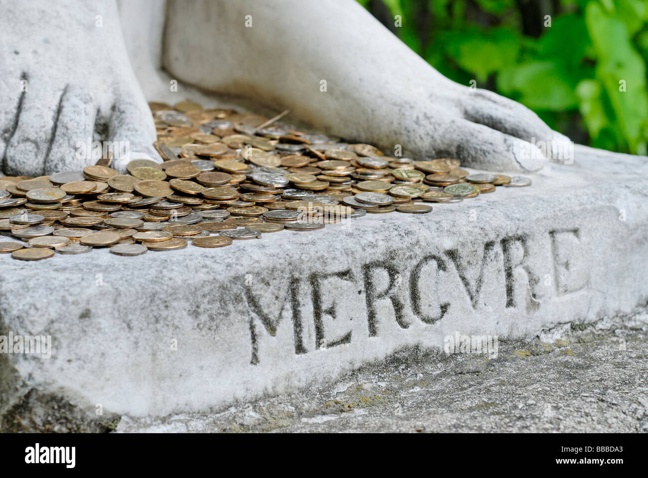 Münzen zu Füßen der Gott Merkur statue Stockfoto