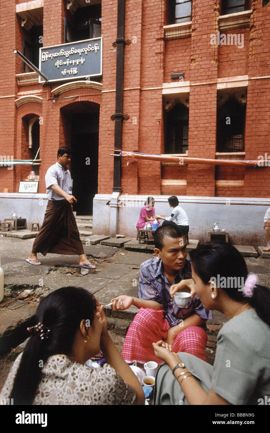 Myanmar (Burma), Yangon (Rangoon), Gruppen von Menschen, die Tee und Snacks außerhalb einer kolonialen Backsteinbau. Stockfoto