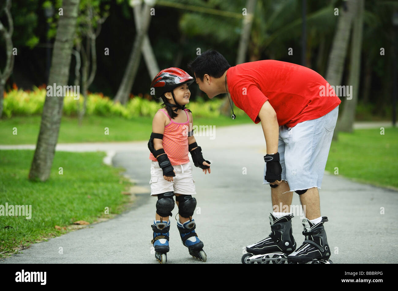 Vater und Tochter tragen Inline-Skates, von Angesicht zu Angesicht stehen Stockfoto