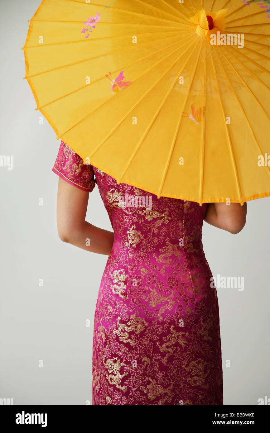 junge Chinesin in Rosa mit gelben Regenschirm cheongsam Stockfoto