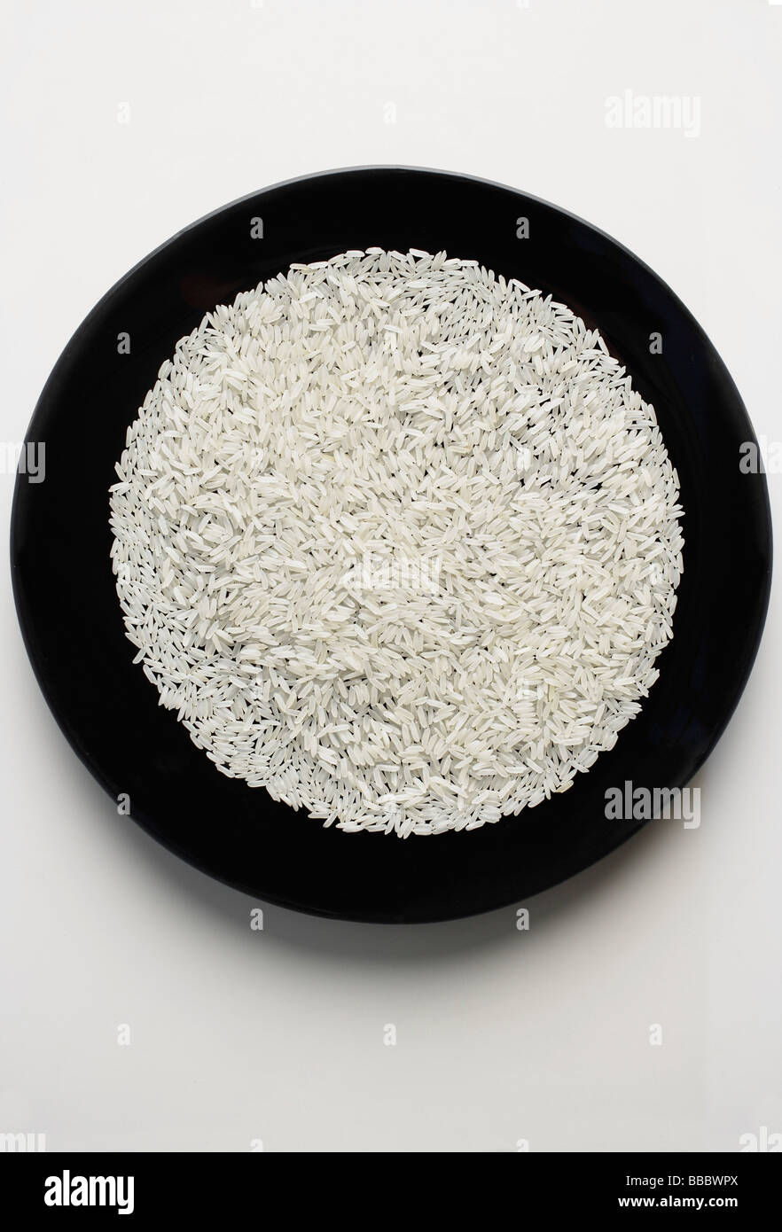 ungekochte Reiskörnern ausgebreitet auf einer schwarzen Platte Stockfoto