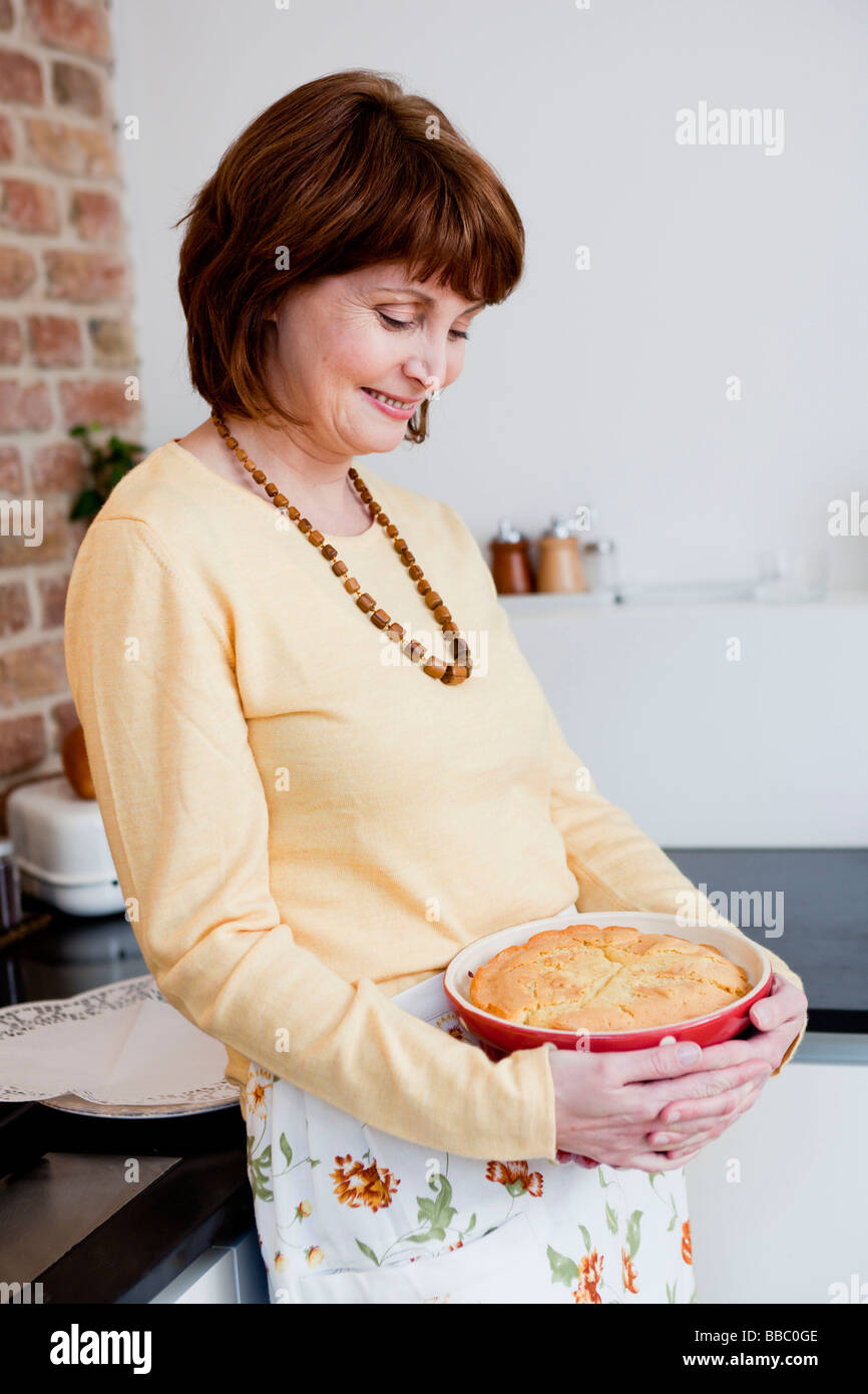 Frau in der Küche anlächelt Kuchen Stockfoto