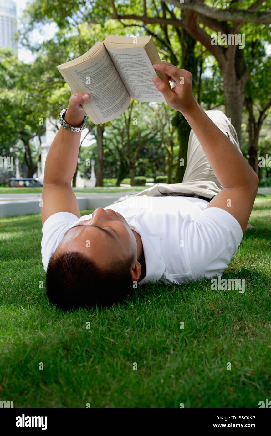 Ein Mann legt sich und liest im park Stockfoto