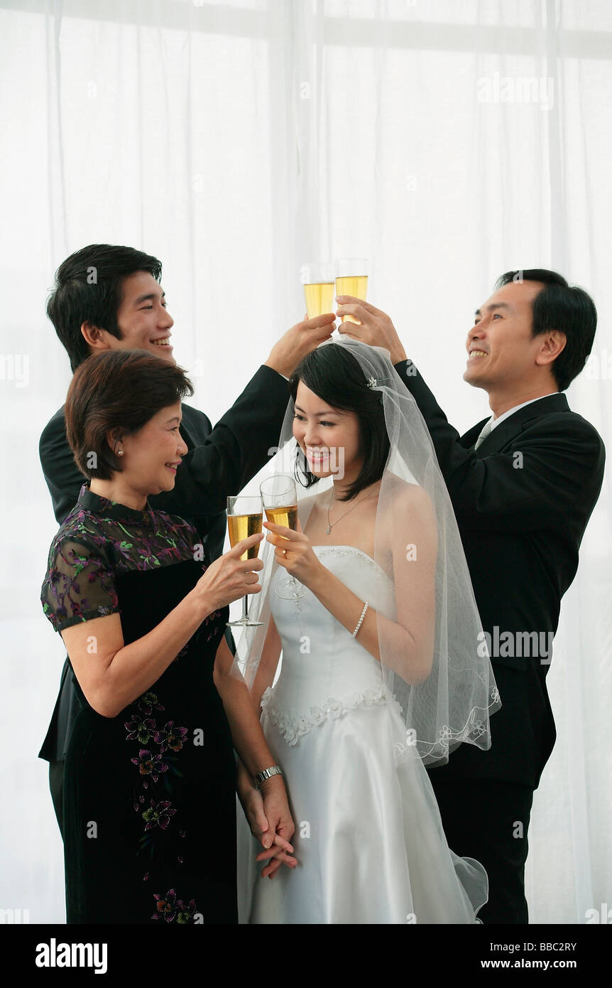 Ein Brautpaar und ihre Familie anstoßen für einen toast Stockfoto