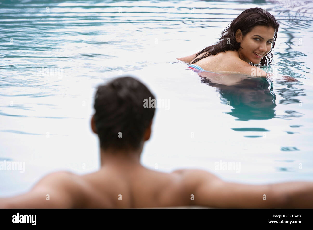 junge Frau, die das Schwimmen im Pool, vorbei an junger Mann Stockfoto