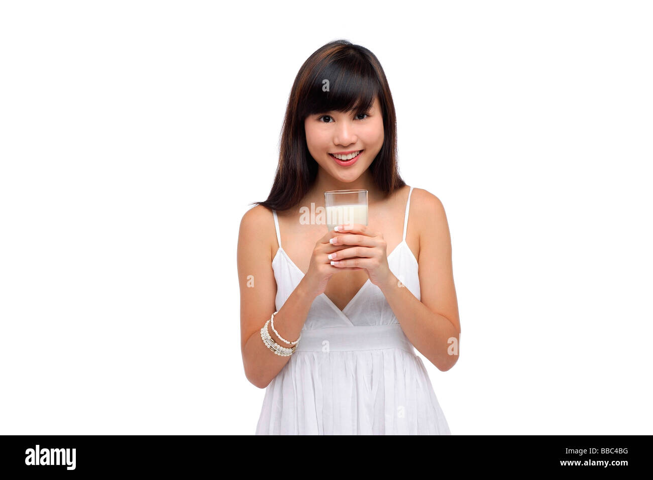 Junge Frau trägt weißes Kleid und hält Glas Milch Stockfoto