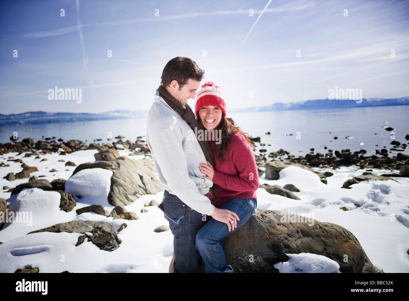 Paar sitzt durch die verschneiten See lachen Stockfoto
