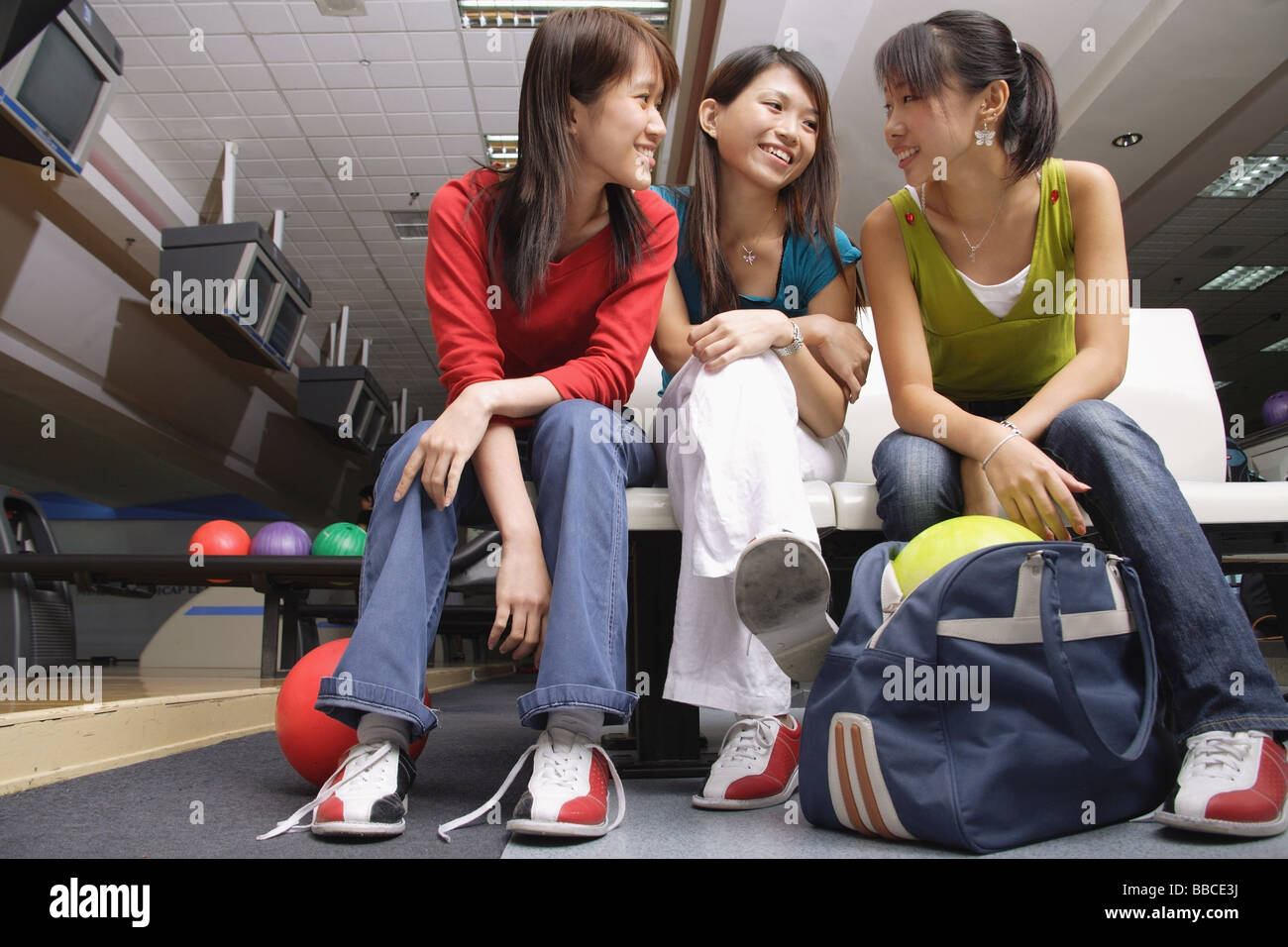 Frauen sitzen nebeneinander in eine Bowlingbahn Stockfoto