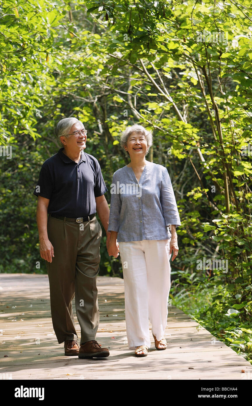 Älteres Paar zu Fuß durch den Park, Hände halten, Lächeln Stockfoto
