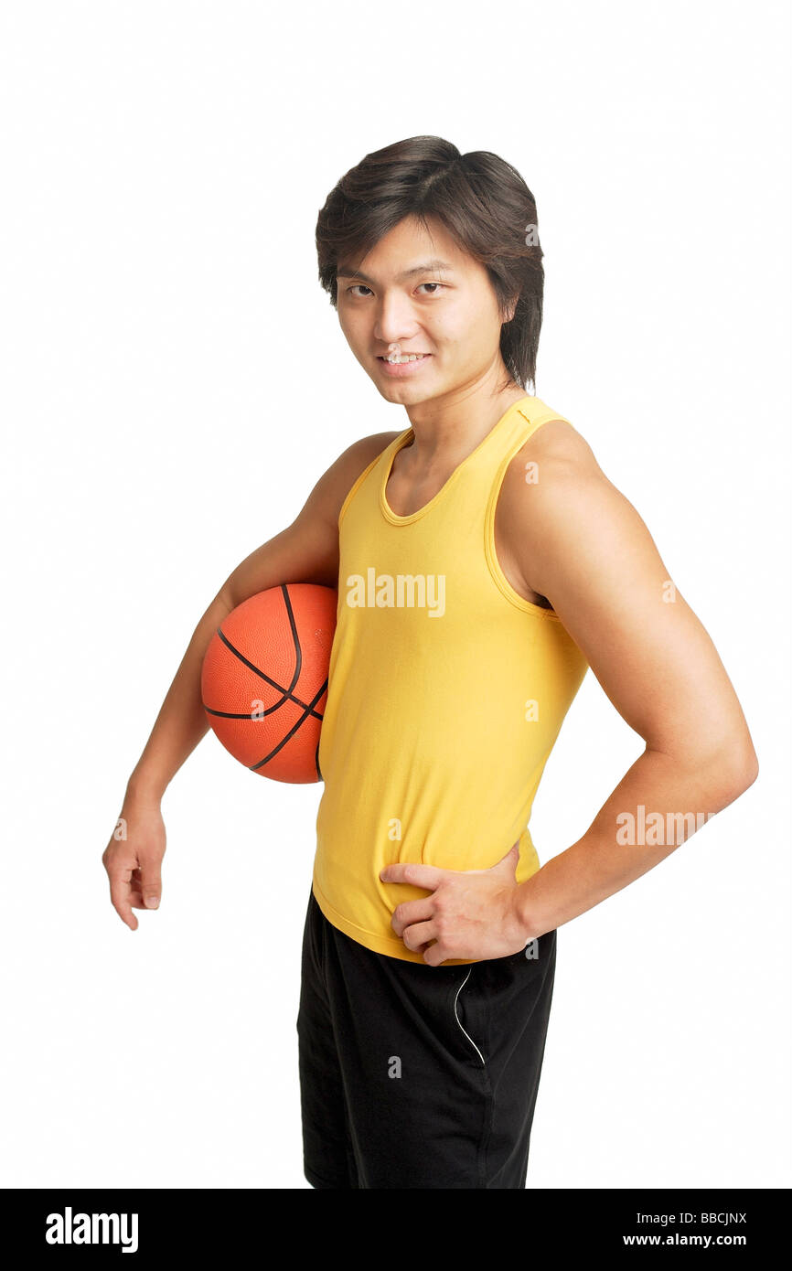 Mann mit Basketball unter Arm, hand auf die Hüfte, Blick in die Kamera Stockfoto