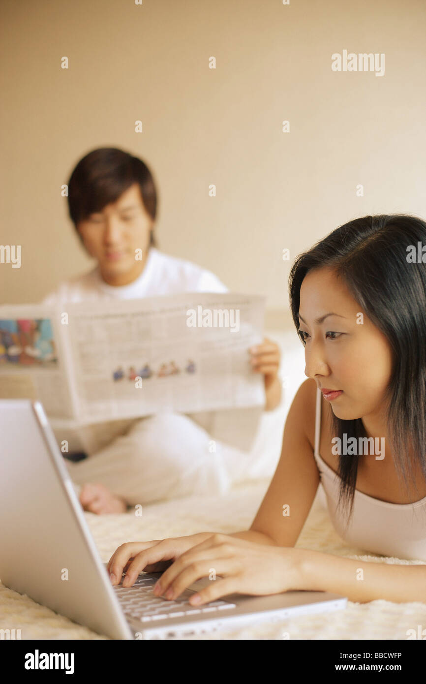 Paar im Schlafzimmer, Mann lesen Zeitung, Frau mit laptop Stockfoto