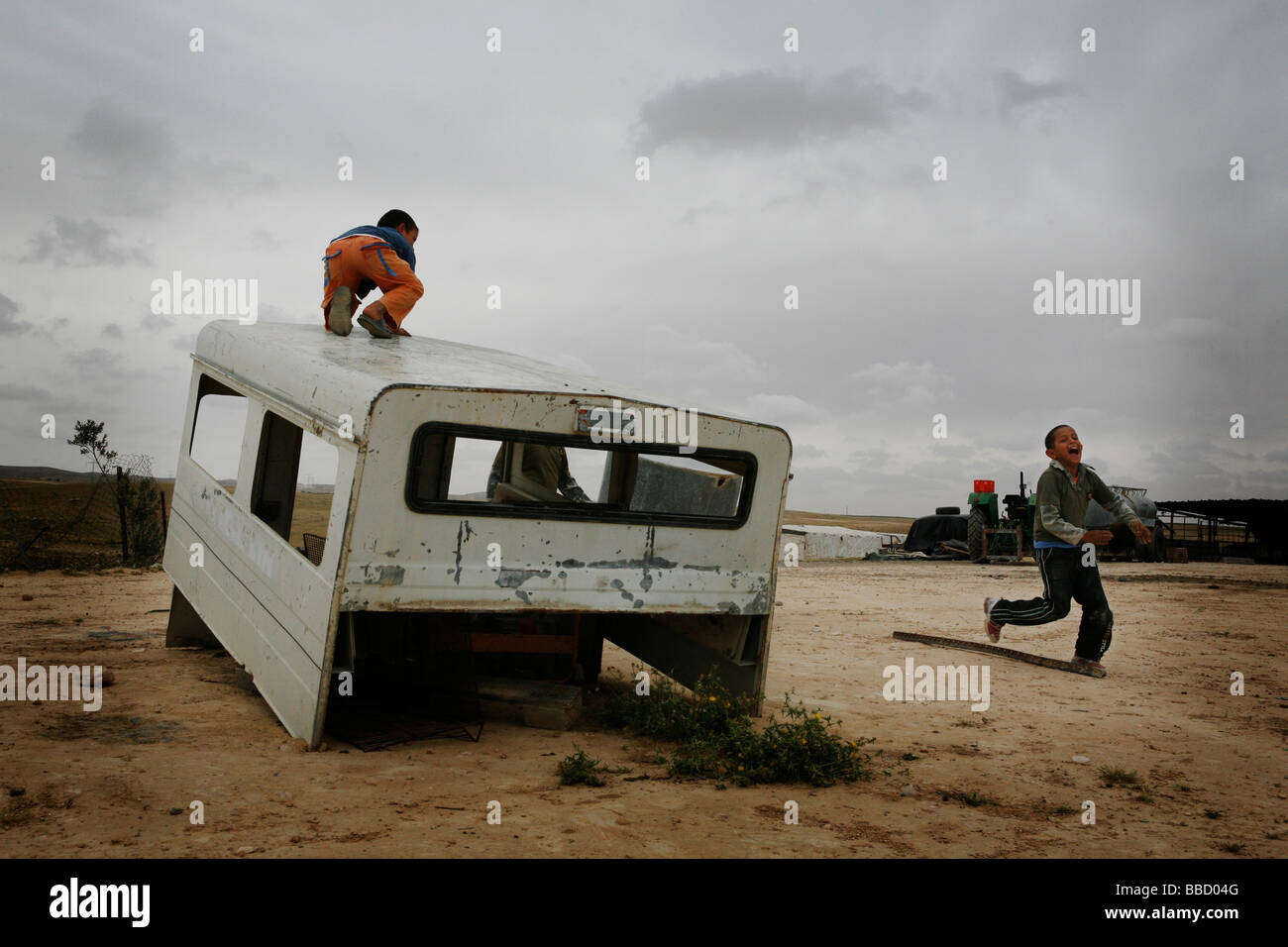 Kinder spielen mit dem Skelett eines Autos in das Dorf El Araqeeb, Israel Stockfoto