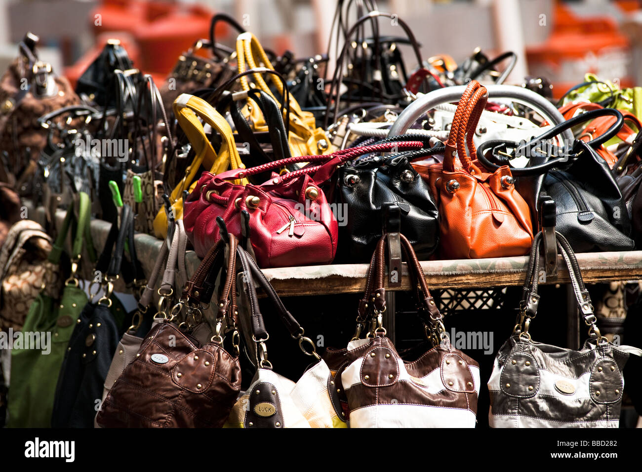 Handtaschen in verschiedenen Farben und Materialien, die gestapelt auf einem shopping Stand auf einer Straße in New York Stockfoto