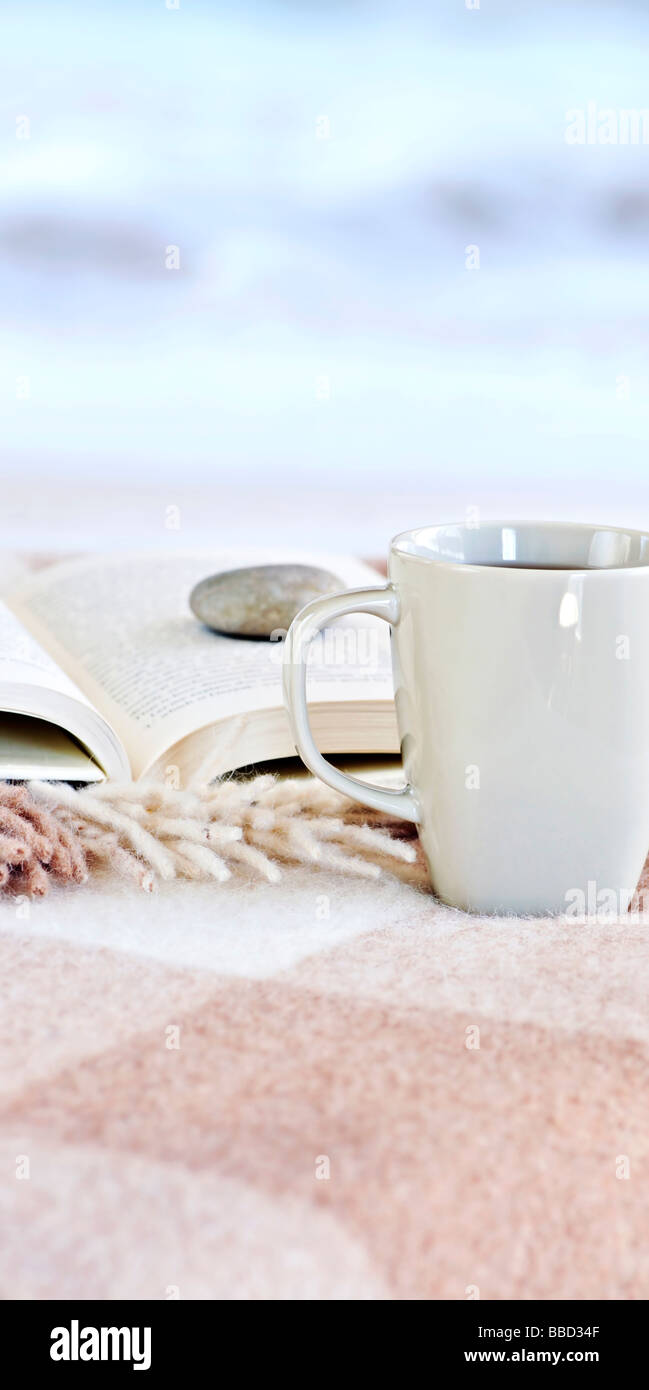 Entspannen mit einem Buch und eine Tasse Tee am Strand Stockfoto