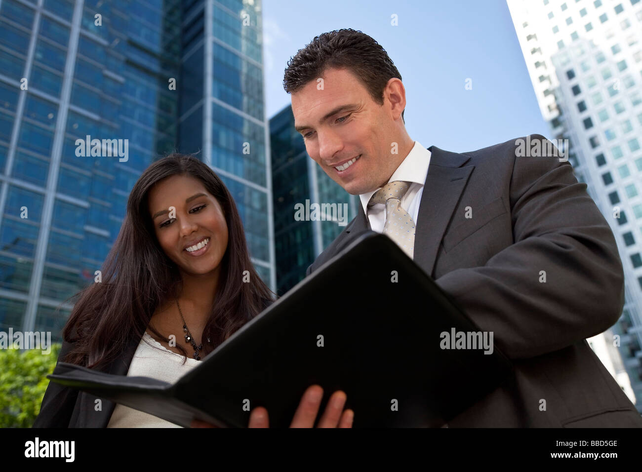 Eine lächelnde Geschäftsfrau und ihr männlicher Kollege Teilnahme an glücklich Geschäftstreffen außerhalb in einer modernen Stadt Stockfoto