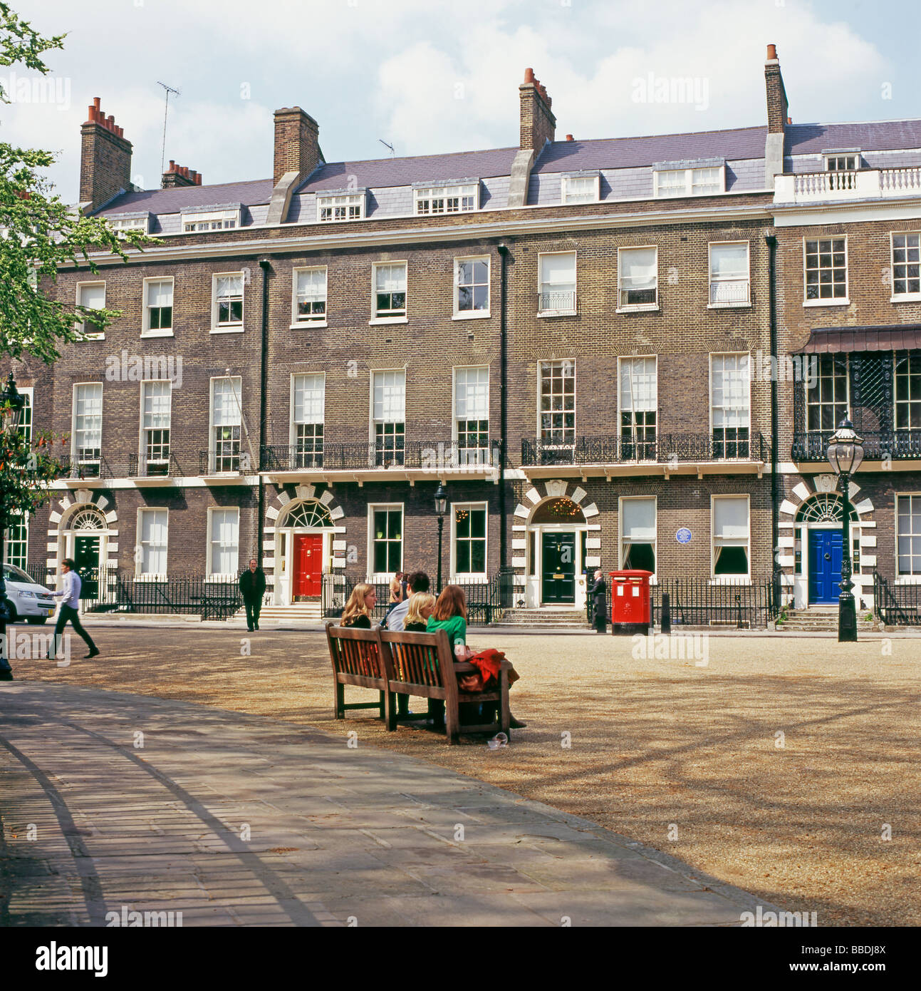 Die Leute sitzen auf einer Bank gegenüber einer Reihe von 18 C Reihenhaus georgianischen Häusern wohnen in Bedford Square Bloomsbury London England UK KATHY DEWITT Stockfoto