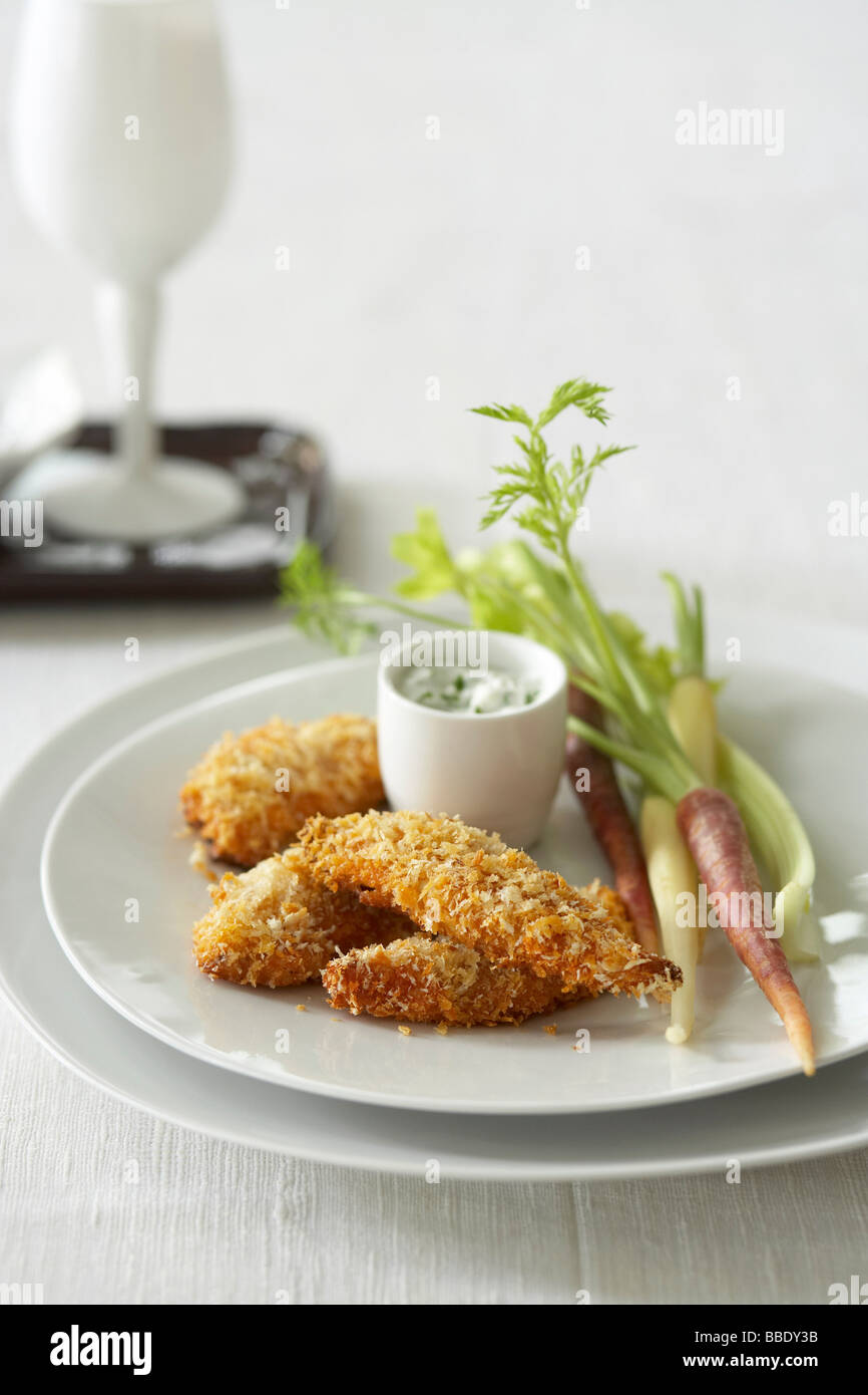 Coconut Crusted Chicken Fingers mit Karotten und Sellerie und Dill-Sauerrahm-Dip Stockfoto