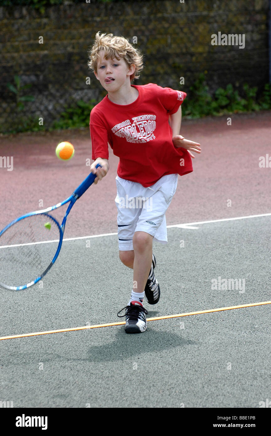 Ein kleiner Junge spielt eine orange Kugel-Tennis-Turnier Stockfoto