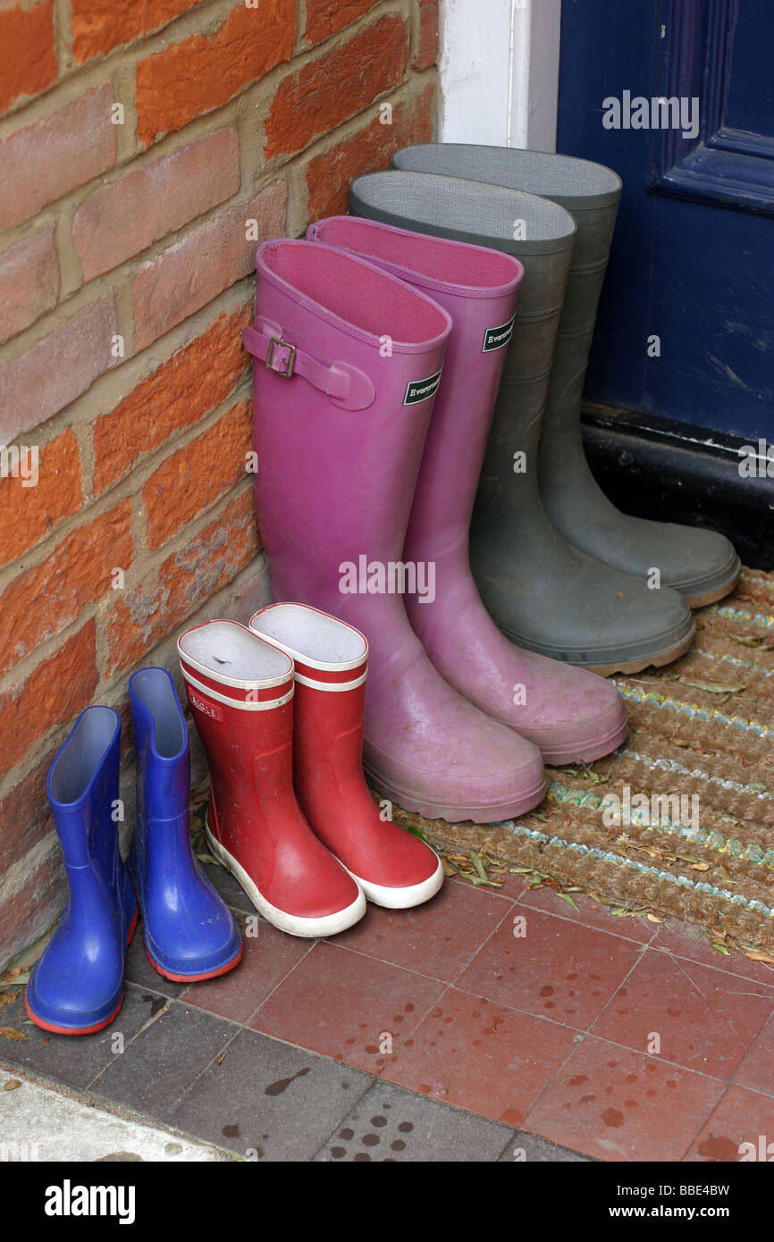 Vier Paar Gummistiefel vor einer Haustür Stockfoto