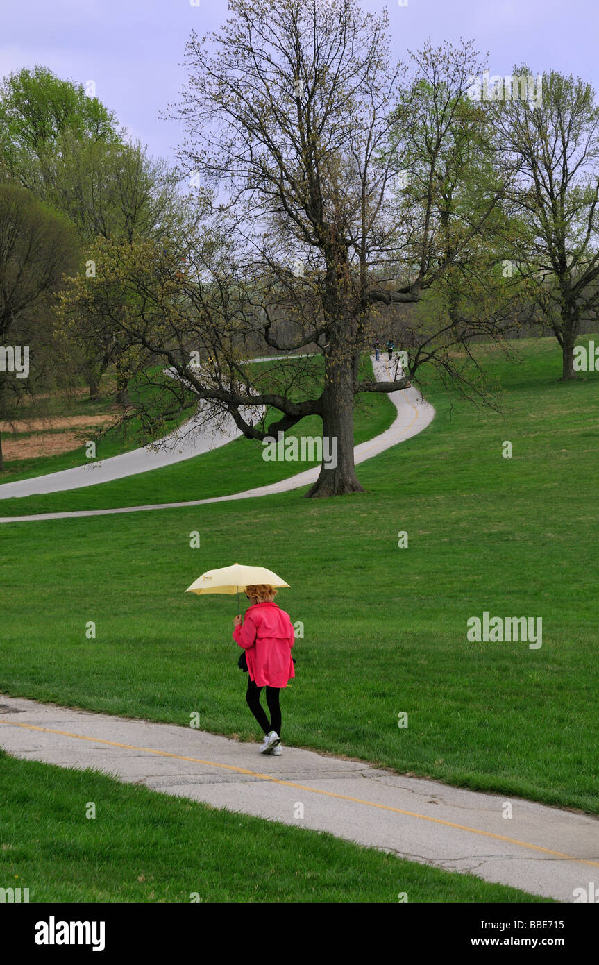 Eine Frau mit Regenschirm geht den asphaltierten Weg in Valley Forge National Historical Park Stockfoto