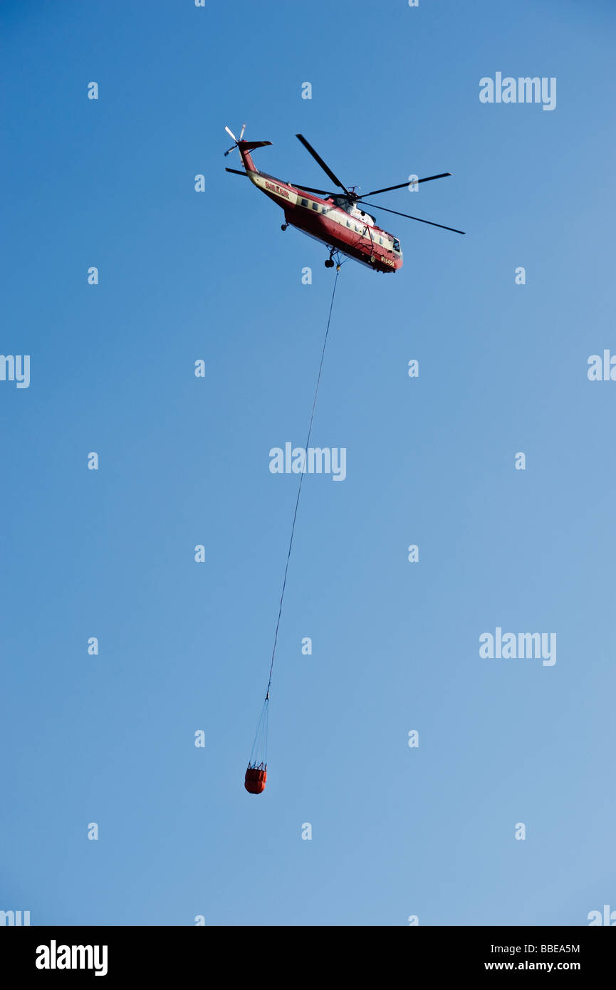 Wasser fallen Brandbekämpfung Hubschrauber fliegt durch Luft Stockfoto