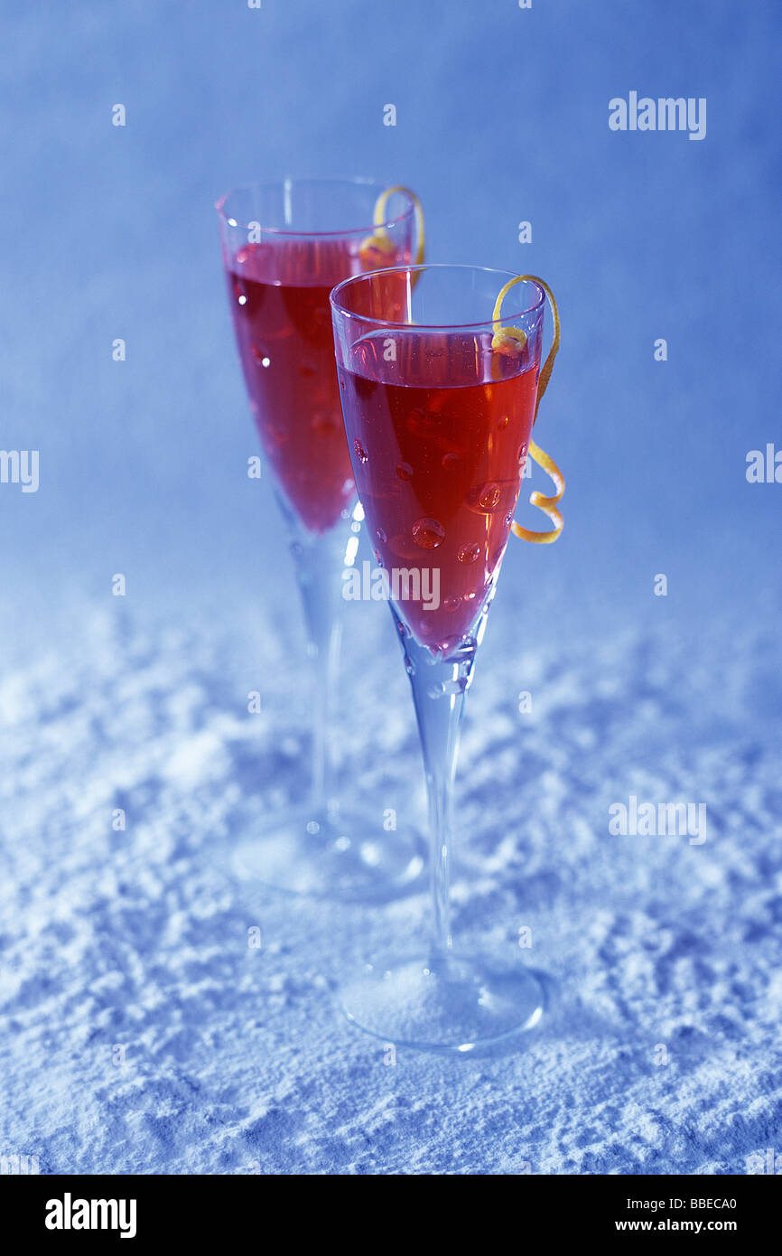 Zwei Cranberry Champagner Getränke mit Zitrone schälen Garnitur auf verschneiten Hintergrund Stockfoto