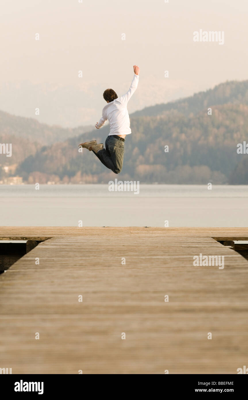 Mann am Dock springen hoch in die Luft, Fuschlsee, Salzburger Land, Österreich Stockfoto