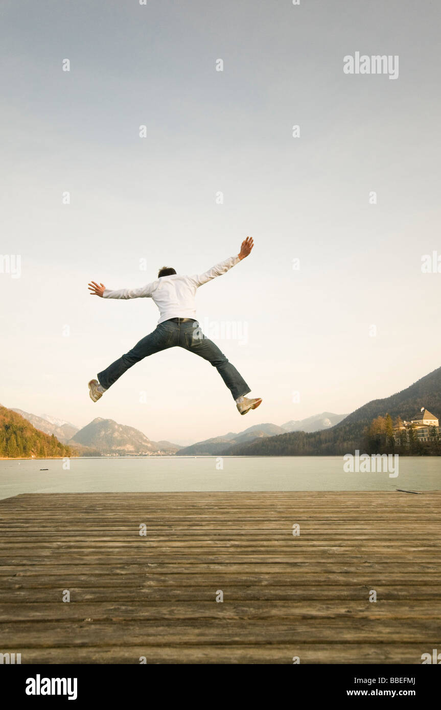 Mann am Dock springen hoch in die Luft, Fuschlsee, Salzburger Land, Österreich Stockfoto