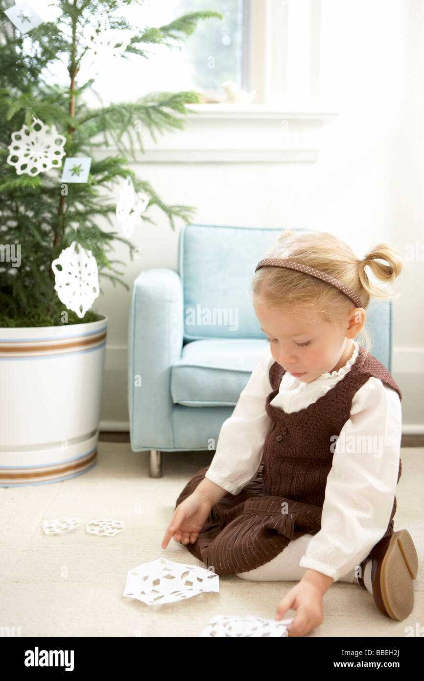 Kleines Mädchen schmücken einen Weihnachtsbaum mit Papier Schneeflocken Stockfoto