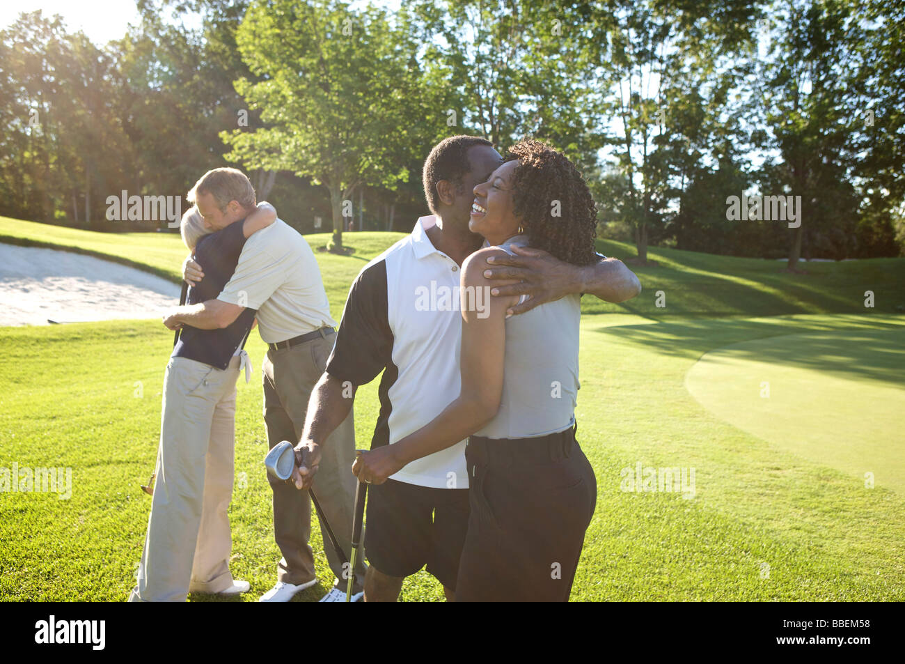 Paare, die umarmt auf Golfplatz Stockfoto