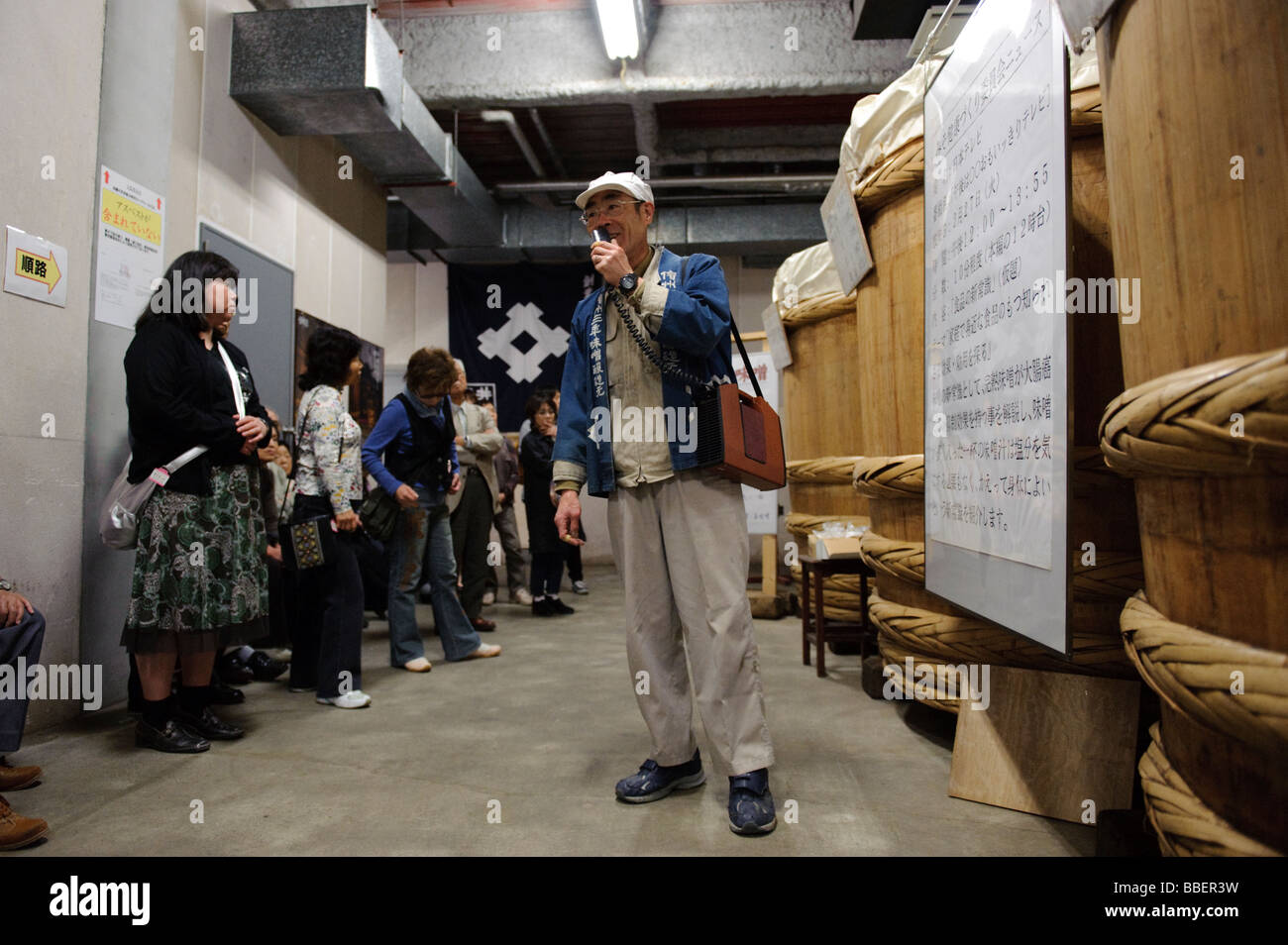 Ein Mitglied des Personals führt Gäste durch den Raum wo die Miso erfolgt, Ishii Miso, Matsumoto, Japan, 19. Mai 2009. Stockfoto