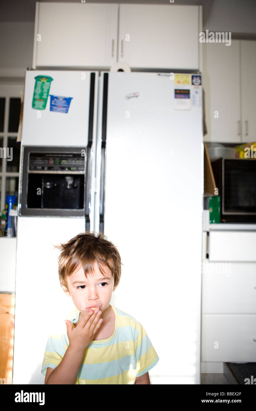 Zwei und ein halb Jahre alten Jungen vor einem Kühlschrank Essen Stockfoto