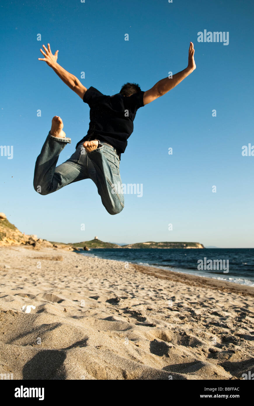 Mann springt am Strand in San Giovanni, Sardinien, Italien Stockfoto